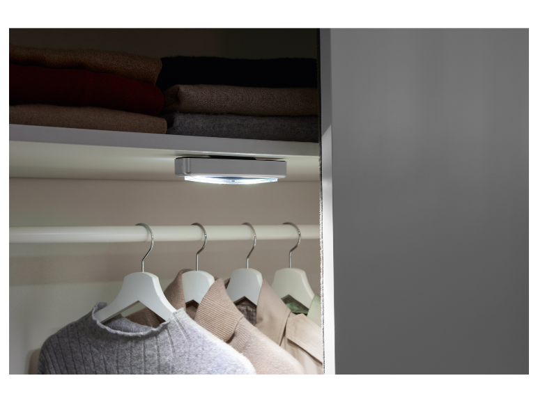 LED osvětlení do skříně, namontované na stropě, osvětluje zavěšené oblečení.
