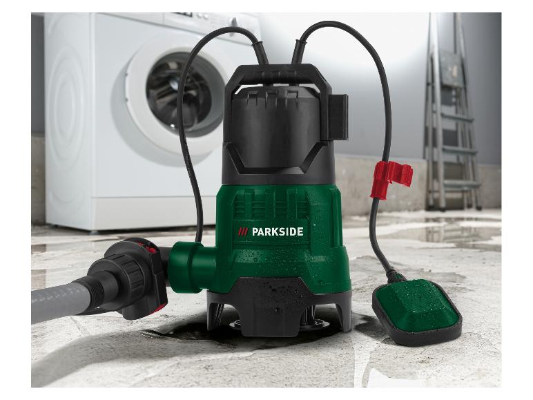 Ponorné čerpadlo s hadicí a plovákovým spínačem na mokré podlaze, s pračkou v pozadí.