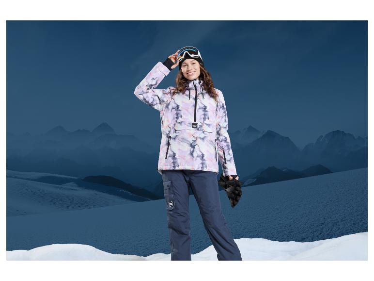 Žena v lyžařské bundě a kalhotách Mountain Warehouse na pozadí hor.