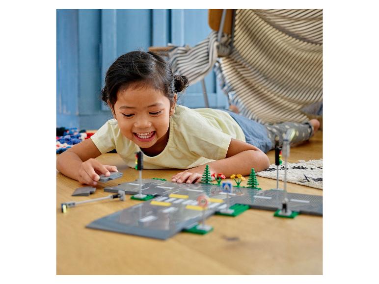 Dívka si hraje s LEGO® City: silnice, semafory a rostliny.