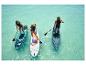 Tři osoby paddleboardují na tyrkysové vodě. Jsou vidět nafukovací SUP prkna.