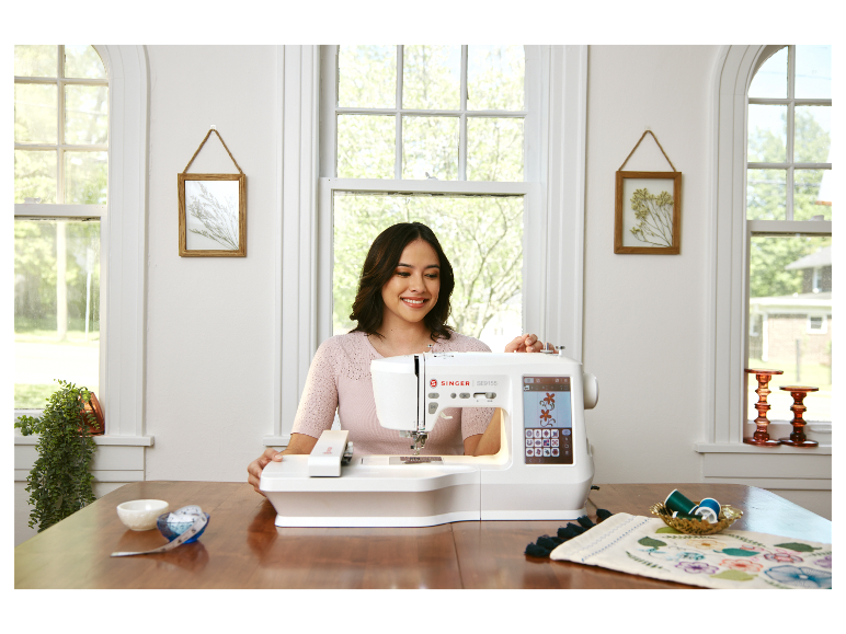 Žena používá šicí stroj Singer SE9155 k vyšívání.