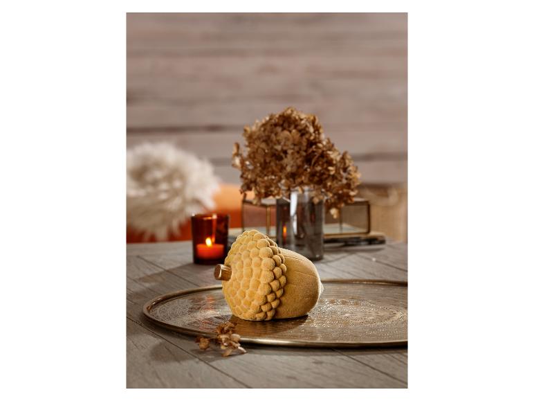 Dekorativní předmět ve tvaru žaludů se žlutým sametovým povrchem na kovovém podnose.