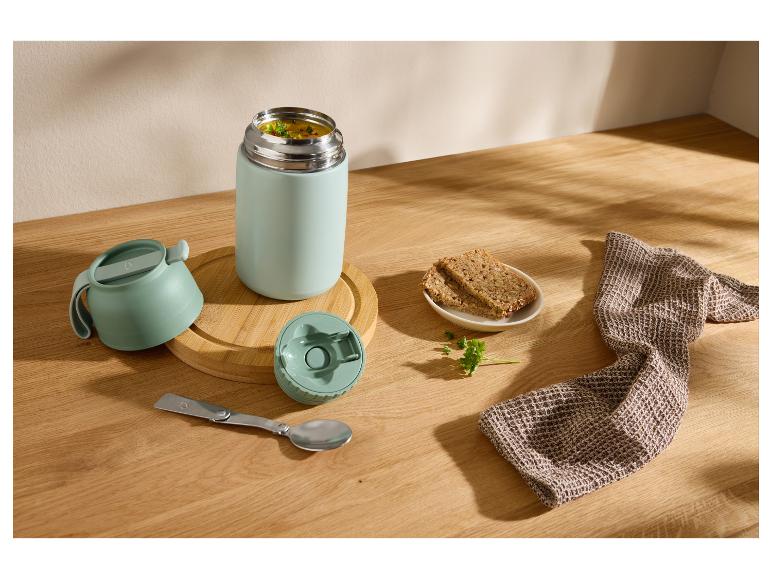 Termoska s polévkou, chlebem a skládací lžící na dřevěném stole.