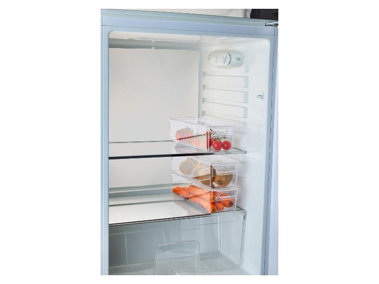 Lednice s průhlednými nádobami plnými rajčat, kiwi a mrkve.