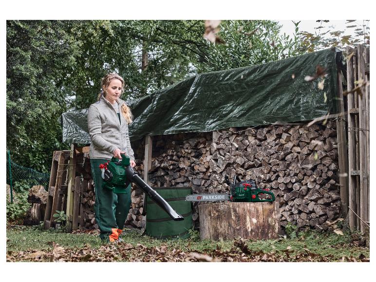 Žena používá foukač listí, s motorovou pilou na dřevěném pařezu.
