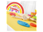 Hlína Play-Doh a dřevěné nástroje na žlutém podkladu.