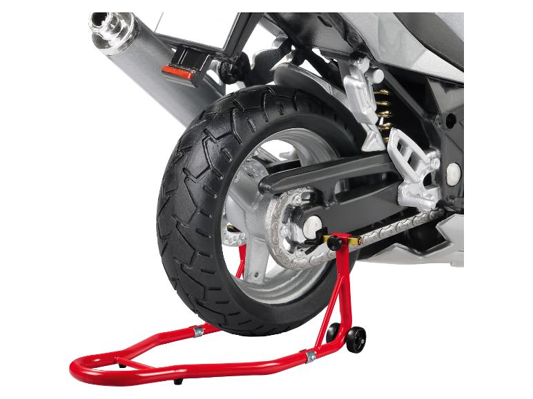 Zadní část motocyklu na červeném stojanu, ukazující pneumatiku, řetěz a výfuk