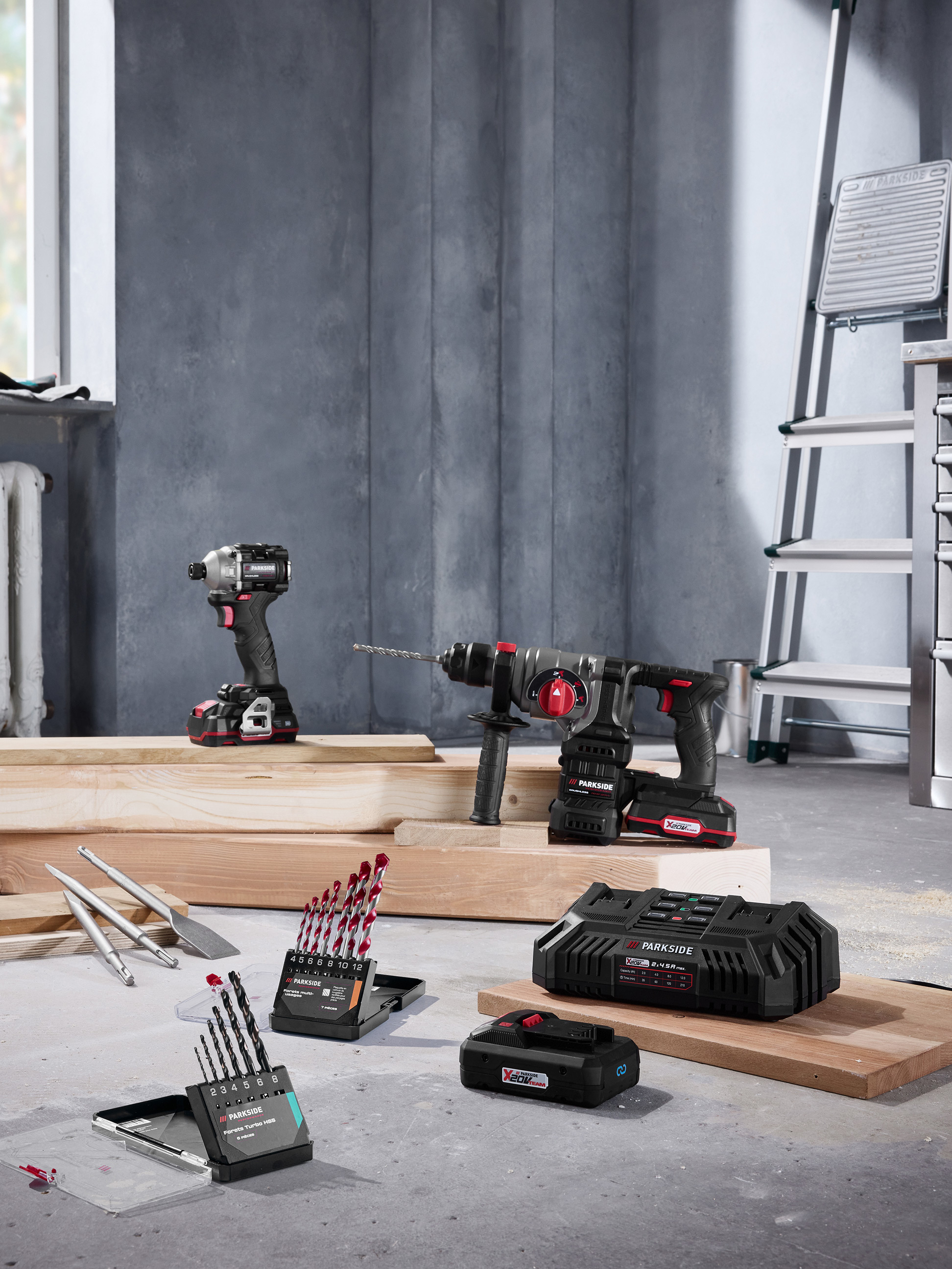 Elektrické nářadí Parkside s vrtačkami, vrtáky a nabíječkou ve stavebním prostředí.
