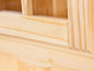 Detail dřevěné skříňky se skleněnými dveřmi.