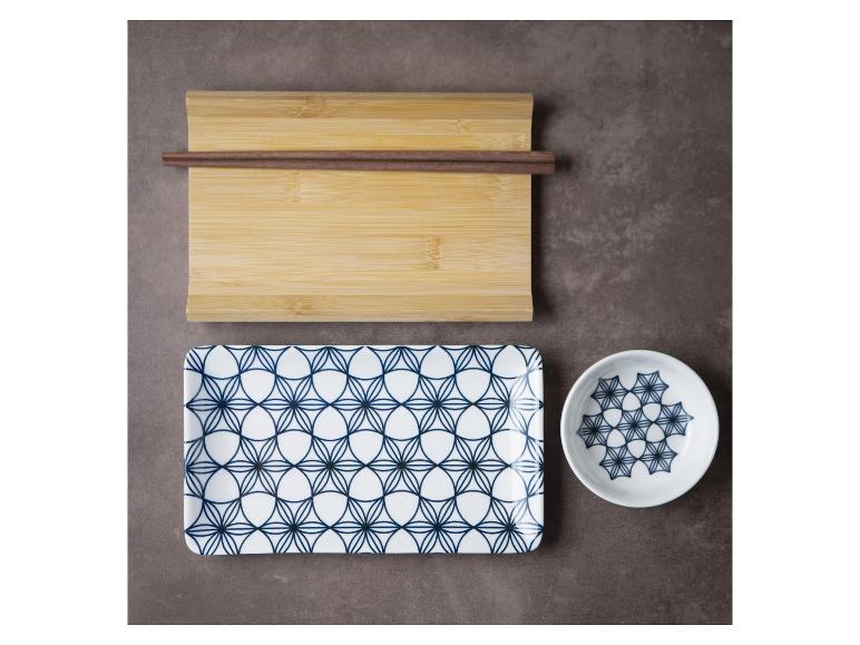 Dřevěná prkénko s hůlkami a sada bílých misek s modrým geometrickým vzorem.