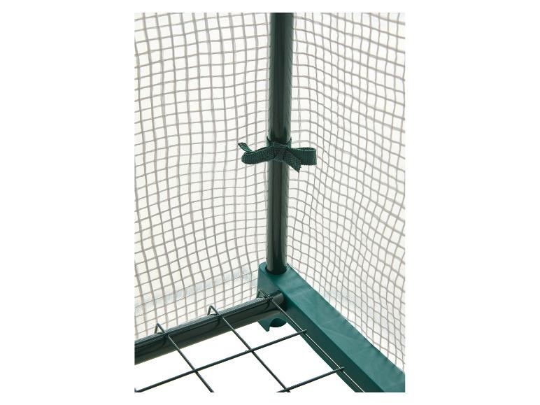 Detail zahradního skleníku se zeleným rámem a průhledným síťovaným potahem.
