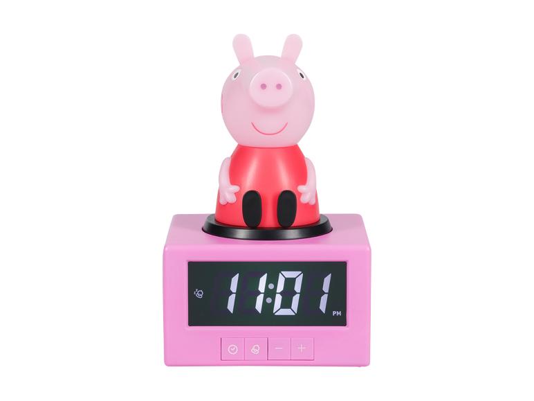 Růžový digitální budík s postavičkou prasete nahoře, zobrazující 11:01 PM.