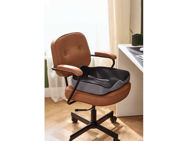 Ergonomický polštář na hnědé kožené kancelářské židli v domácí kanceláři.