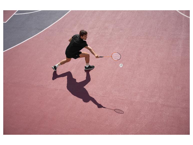 Muž v černém hraje badminton na růžovo-šedém kurtu.