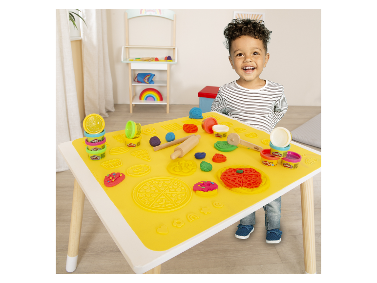 Dítě si hraje s modelovací hmotou Play-Doh u stolu se speciální podložkou.