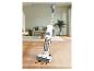 Bezdrátový vysavač čistí skvrnu od kávy na dřevěné podlaze.