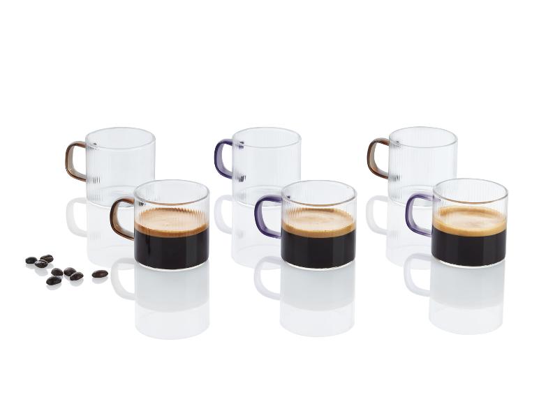 Espresso v  skleněných šálcích s fialovými rukojetěmi.