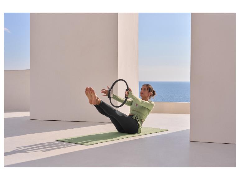 Žena ve funkčním topu CRIVIT cvičí pilates s kruhem na podložce.