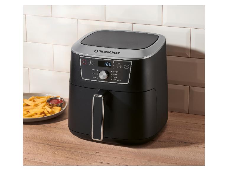 Černá horkovzdušná fritéza s digitálním displejem ukazujícím 180°C, vedle talíře hranolek a kečupu.