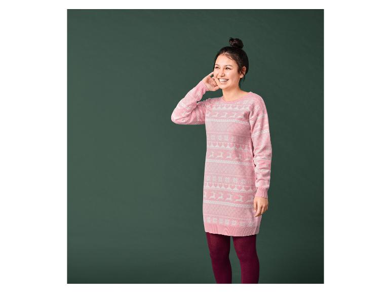 Žena v růžovém vánočním svetru s jeleny a sněhovými vločkami.