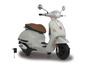 Bílý elektrický skútr Vespa s nabíječkou.