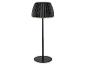 Černá stojací lampa s plisovaným stínidlem, vyzařující teplou záři.