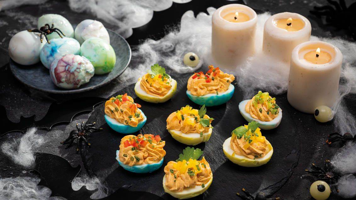 Halloweenské ďábelské vejce s pavouky, svíčkami a pavučinami.
