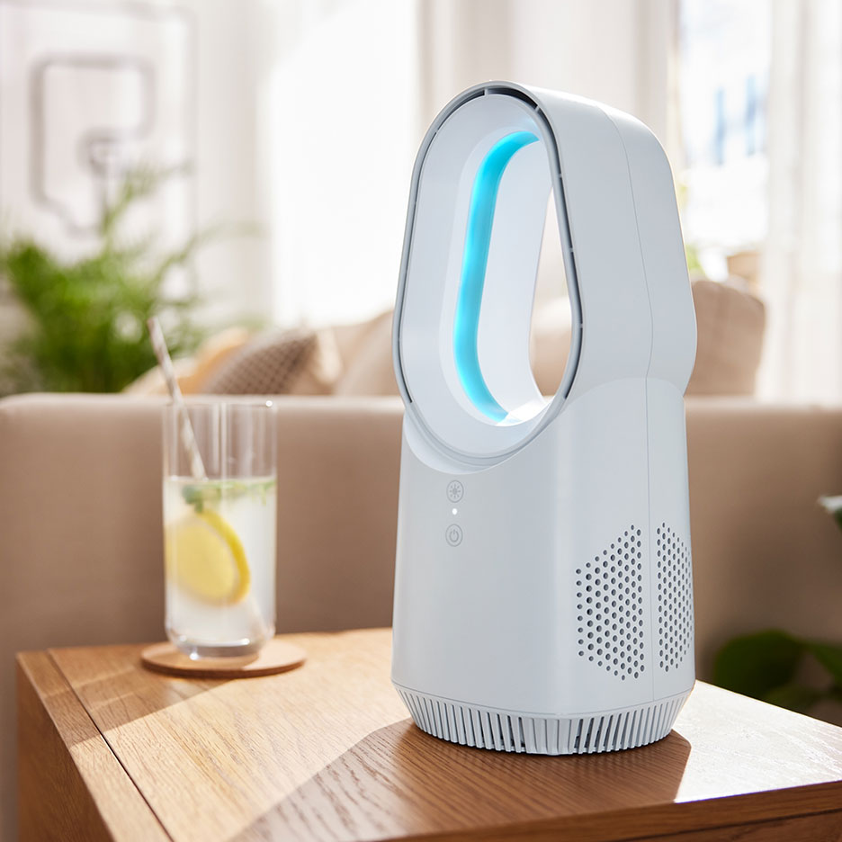 Bílý bezlopatkový ventilátor s modrým světlem na dřevěném stole s nápojem.