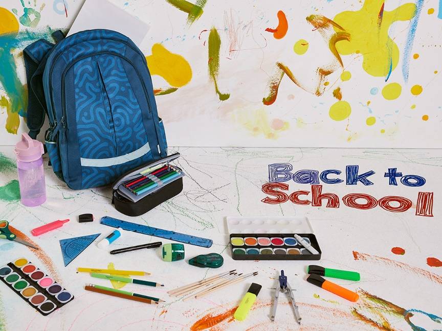 Batoh a školní potřeby na pozadí s nápisem „Back to School“.