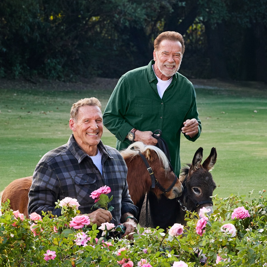 Dva muži se usmívají s poníkem a oslem, jeden drží růži.