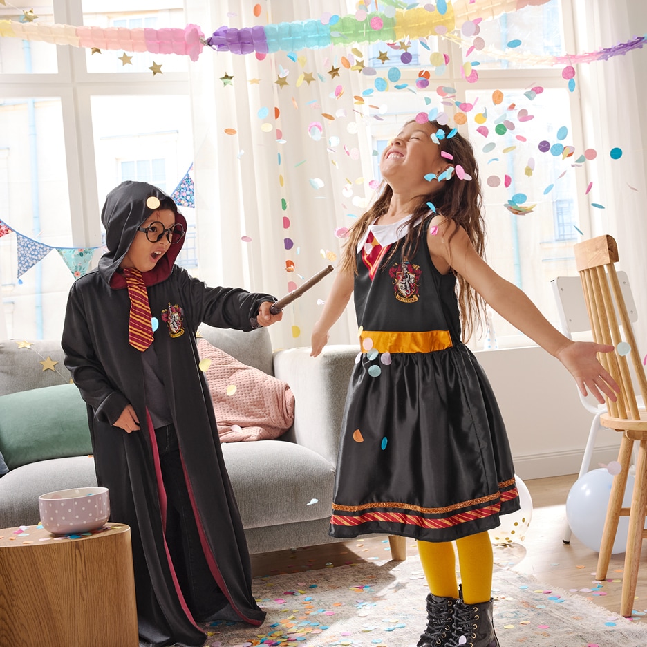 Dvě děti v kostýmech Harryho Pottera si hrají s konfetami.