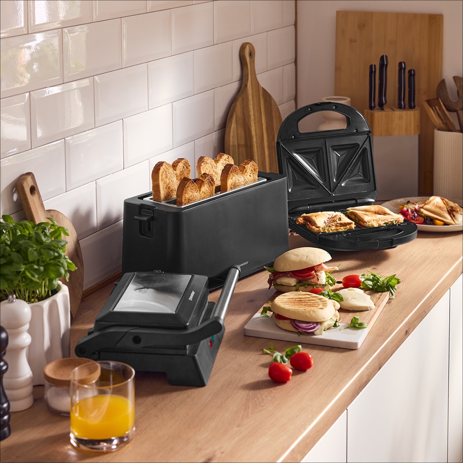 Kuchyňská linka s topinkovačem, sendvičovačem a kontaktním grilem, připravené toasty a sendviče.