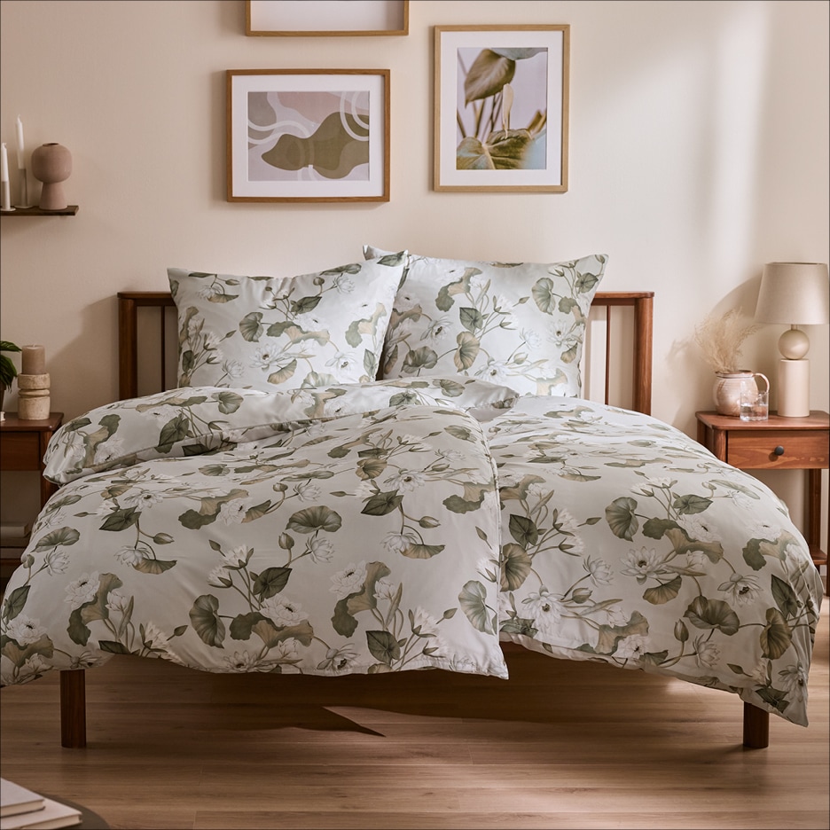 Postel s povlečením s květinovým vzorem, noční stolky a obrazy na stěně.