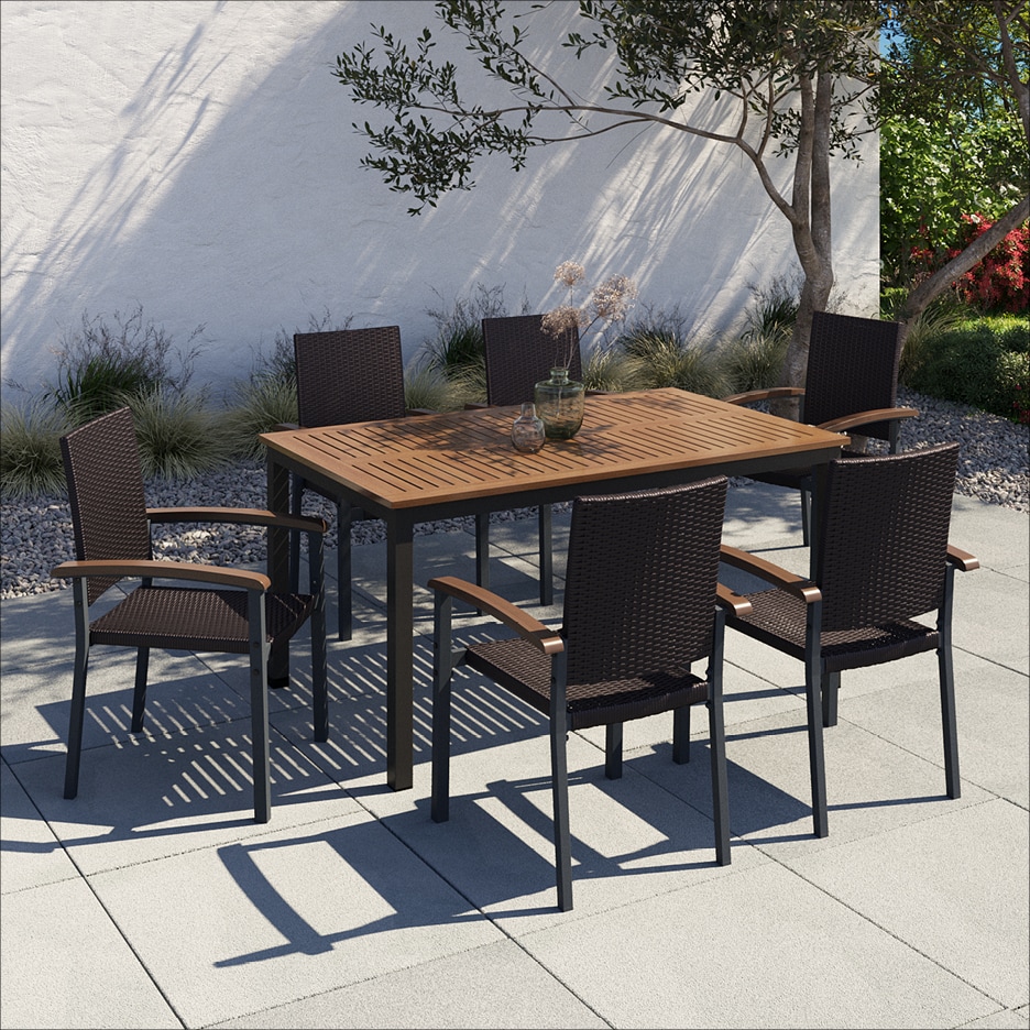 Dřevěný zahradní stůl se šesti tmavě hnědými proutěnými židlemi na terase.