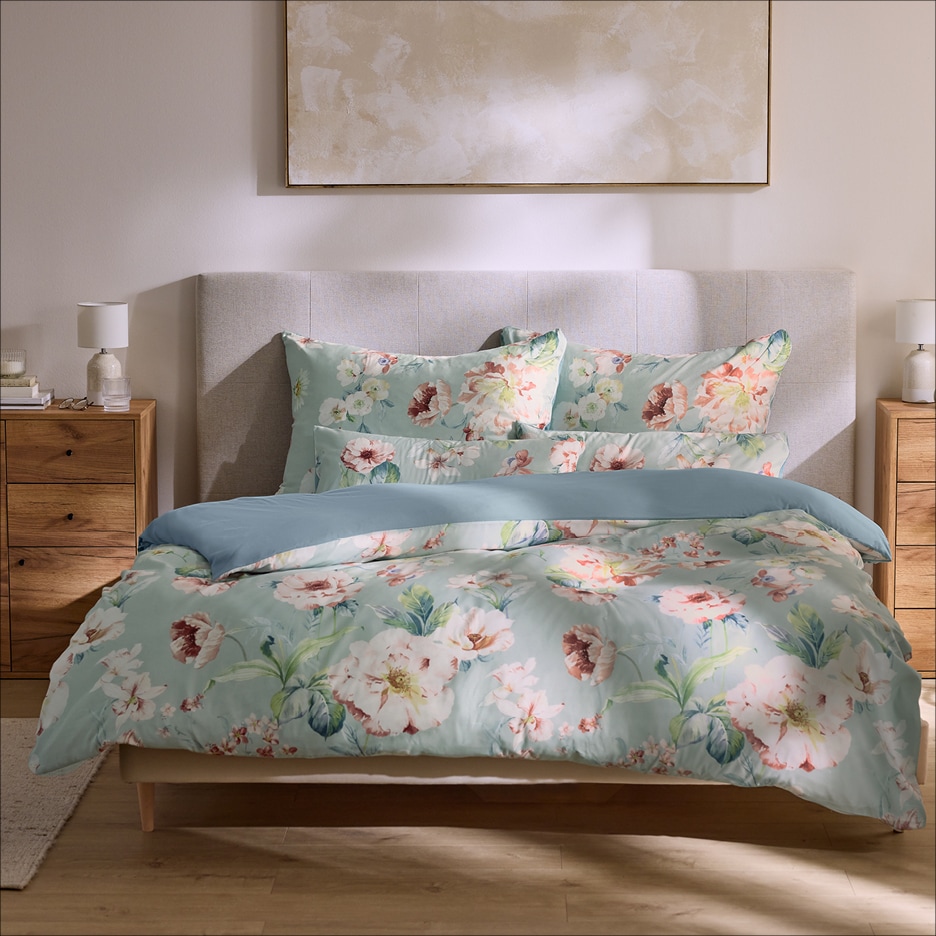 Ložnice s postelí s květinovým povlečením a dřevěnými nočními stolky.