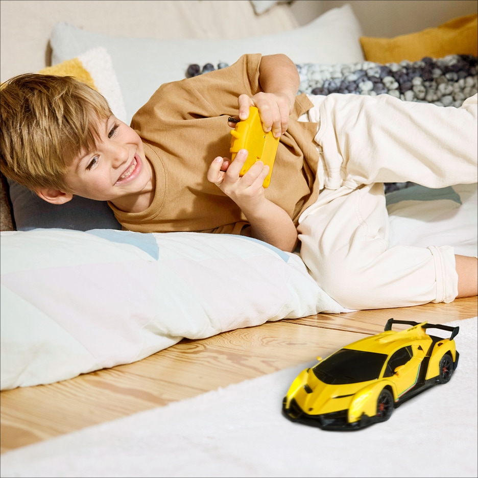 Chlapec si hraje s dálkově ovládaným žlutým sportovním autem.