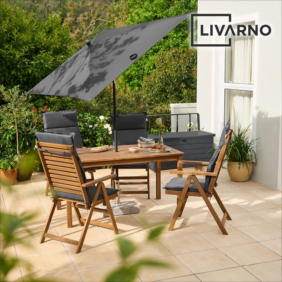 Dřevěný zahradní nábytek s šedými polštáři a slunečníkem na terase.