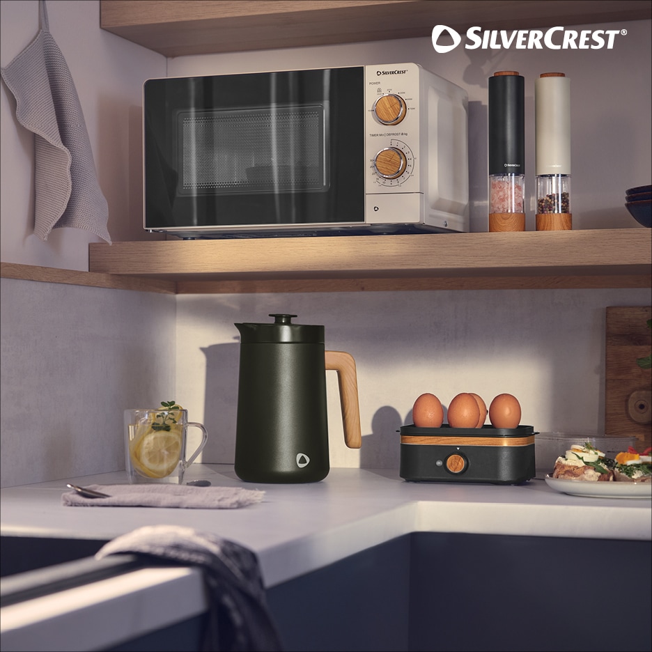 Kuchyňská linka s mikrovlnnou troubou, konvicí, vajíčky a mlýnky na koření.