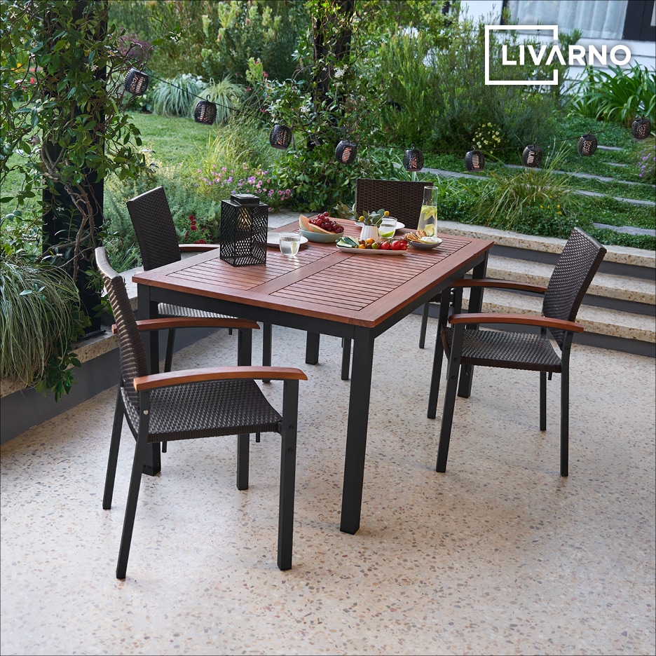 Dřevěný zahradní stůl a židle s proutěným opěradlem na terase s občerstvením.