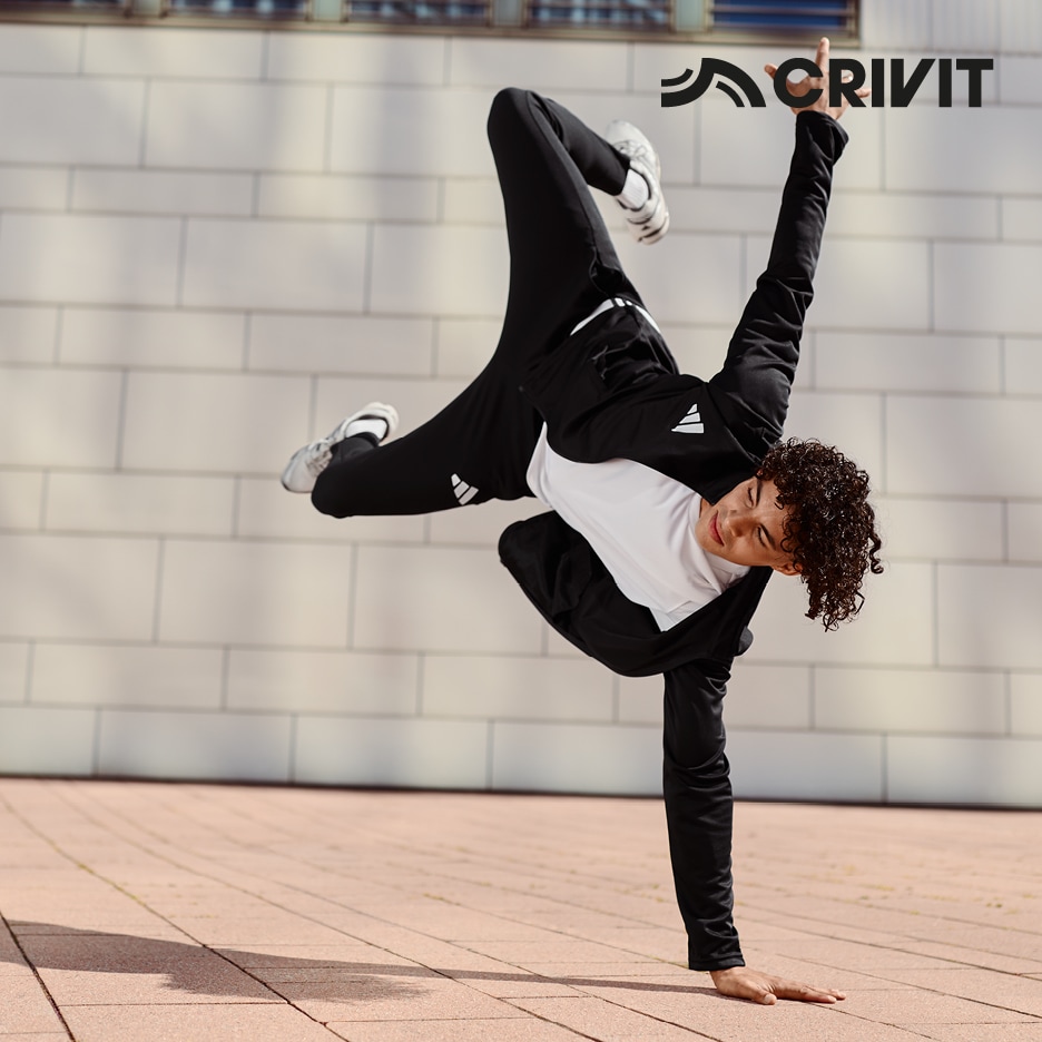 Mladý muž v černém sportovním oblečení předvádí breakdance na jedné ruce.