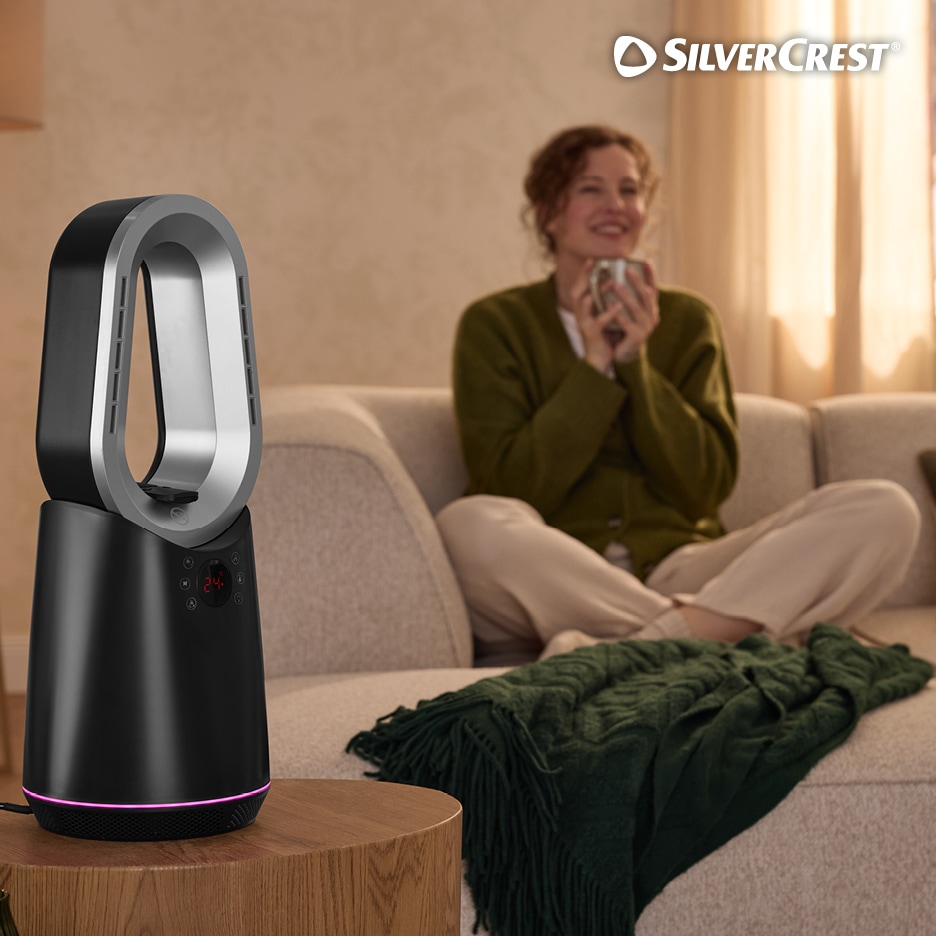 Bezlopatkový teplovzdušný ventilátor na stolku v obývacím pokoji s relaxující ženou.