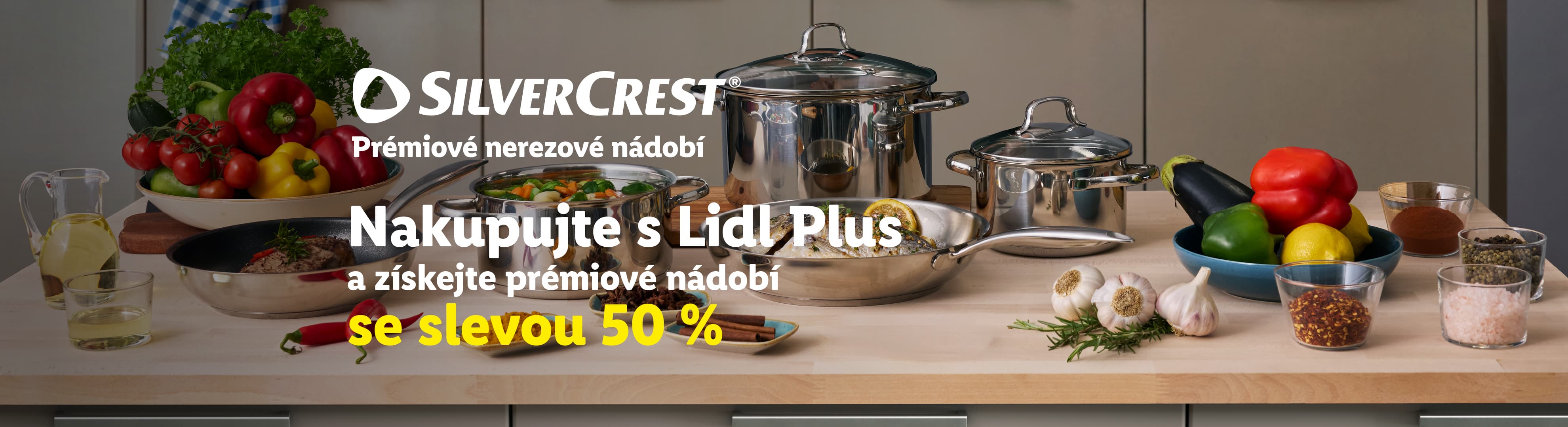 Nerezové nádobí Silvercrest s 50% slevou pro členy Lidl Plus, obklopené čerstvou zeleninou a kořením.