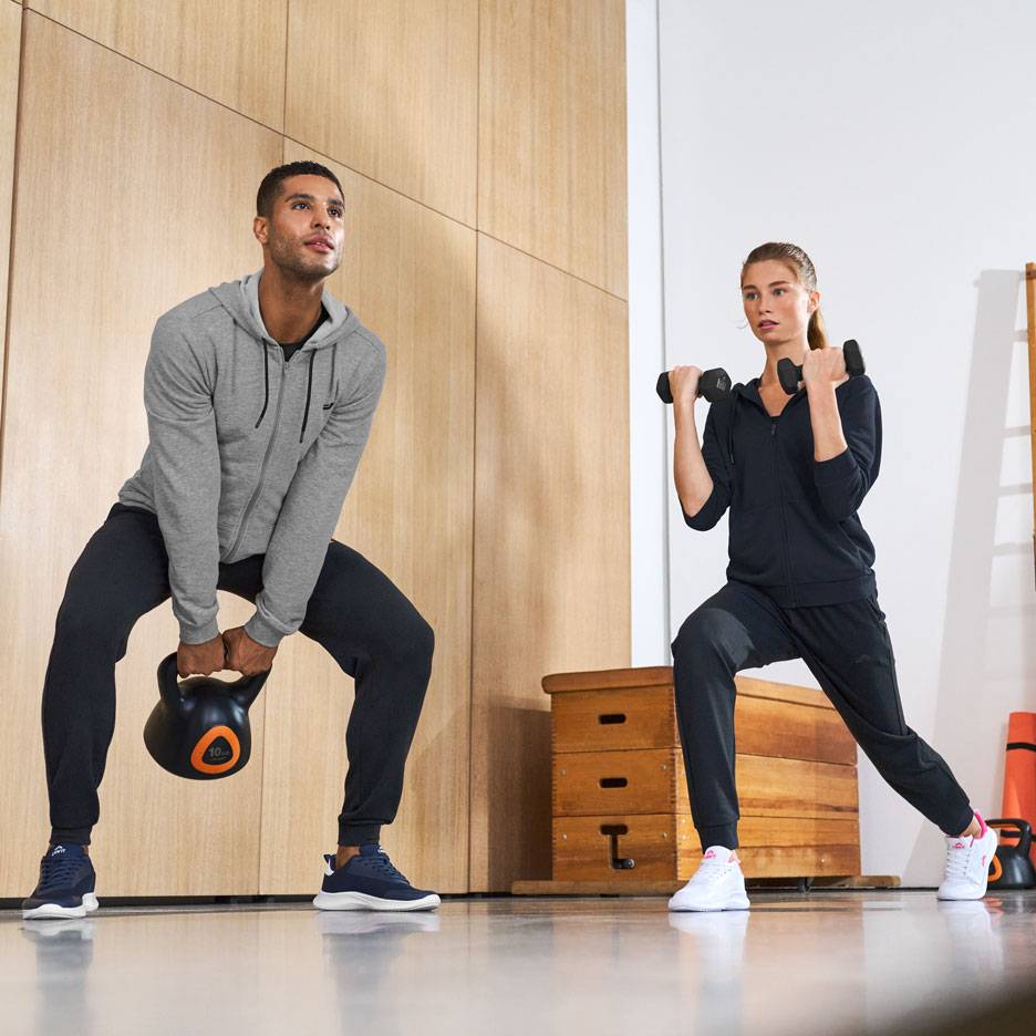 Muž a žena ve sportovním oblečení, cvičící s kettlebellem a činkami.
