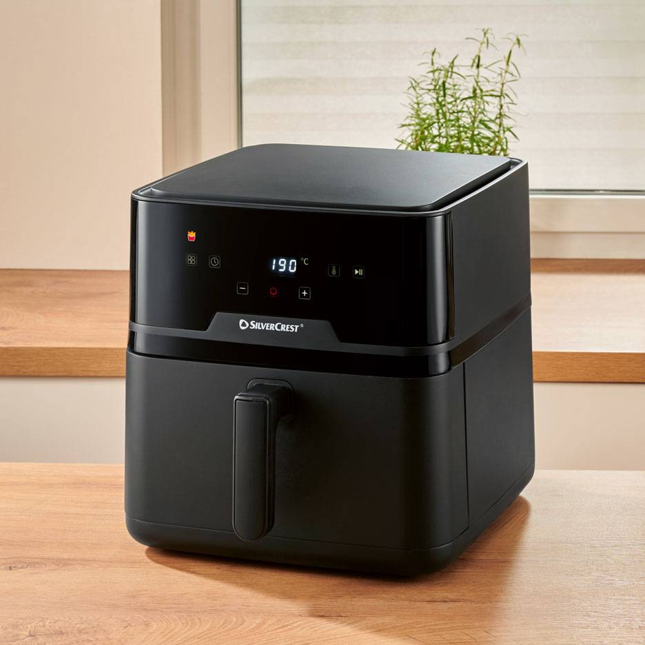 Černá digitální horkovzdušná fritéza na dřevěném stole, na displeji 190 °C.