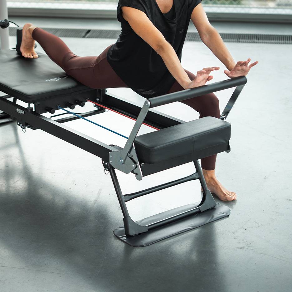 Žena cvičící na stroji na Pilates ve sportovním oblečení