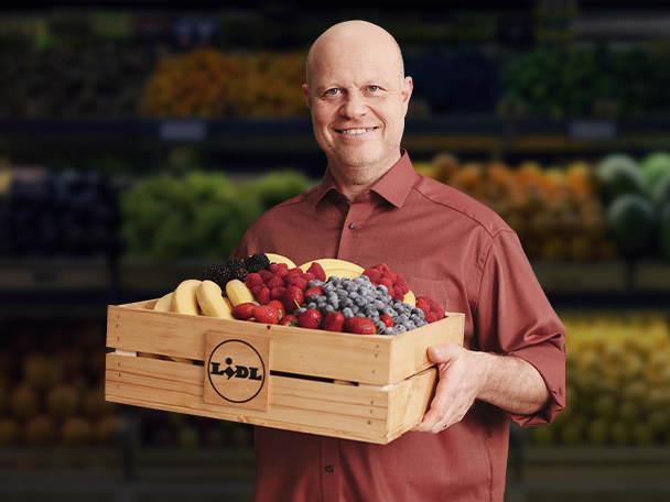 Lidl čerstvé ovoce: banány, maliny, borůvky a jahody v dřevěné bedně.