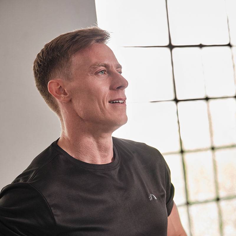 Muž v černém tričku se dívá k oknu.