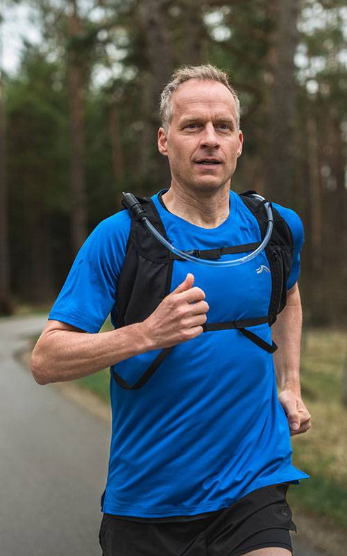 Muž běží s hydratační vestou Salomon.