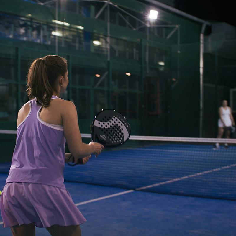 Padel: Žena s raketou na kurtu.